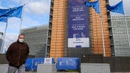 Ein Mann mit einer Schutzmaske geht in Brüssel am Sitz des Europäischen Rats vorbei. Ein Mann mit einer Schutzmaske geht in Brüssel am Sitz des Europäischen Rats vorbei.