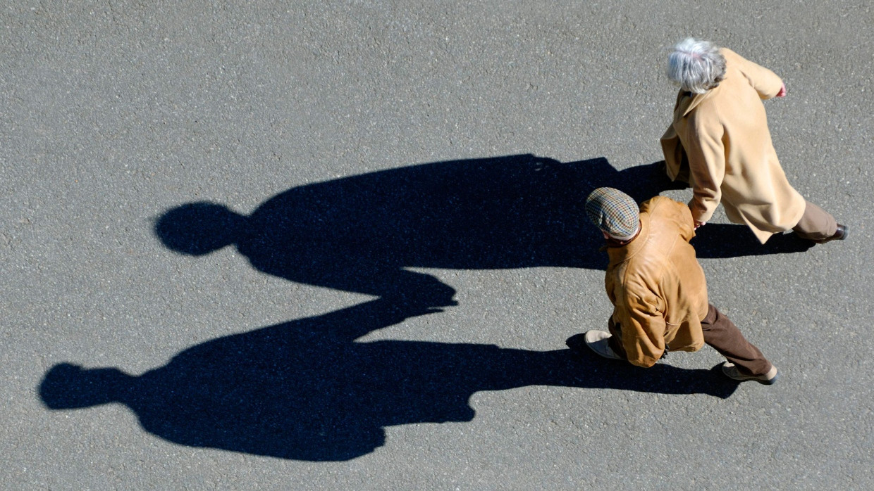 Ein Paar Rentner läuft über eine Straße.