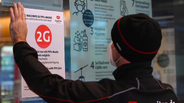Bayern: Ein Mitarbeiter der Zugspitzbahn klebt einen 2G Hinweis an die Eingangstür der Talstation.